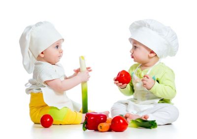 18792402 - babies boy and girl wearing a chef hat with healthy  food vegetables